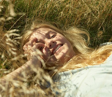 A smiling girl or a woman laying down in the nature