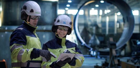 Man and woman wearing personal protective equipment with Uniper and Fortum logo watching a document inside a power plant.