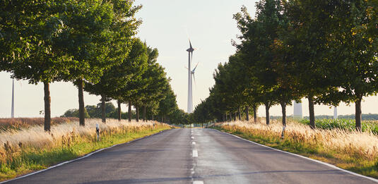 Wind turbines in horizon at the end of a road