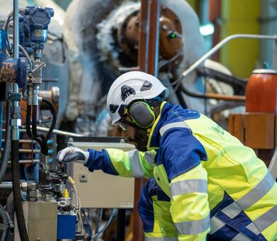 A man working at power plant checking the turbine's control and protective systems.